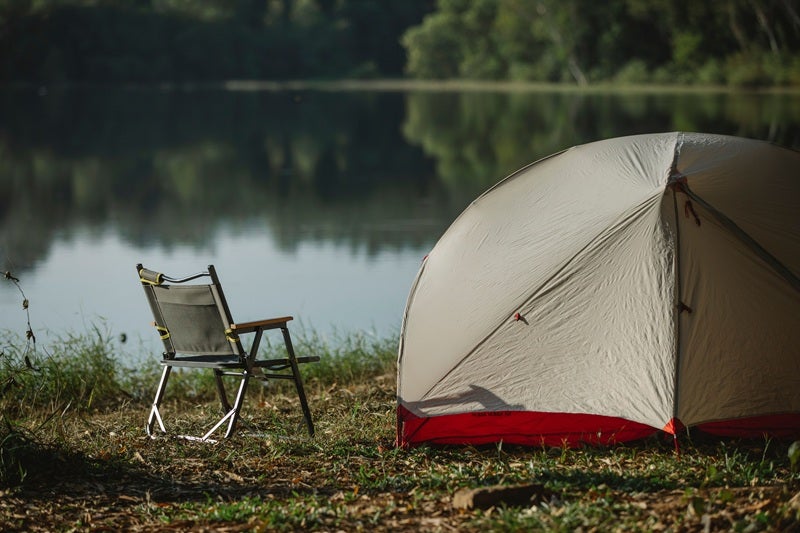 Camping tent and chair in front of a river